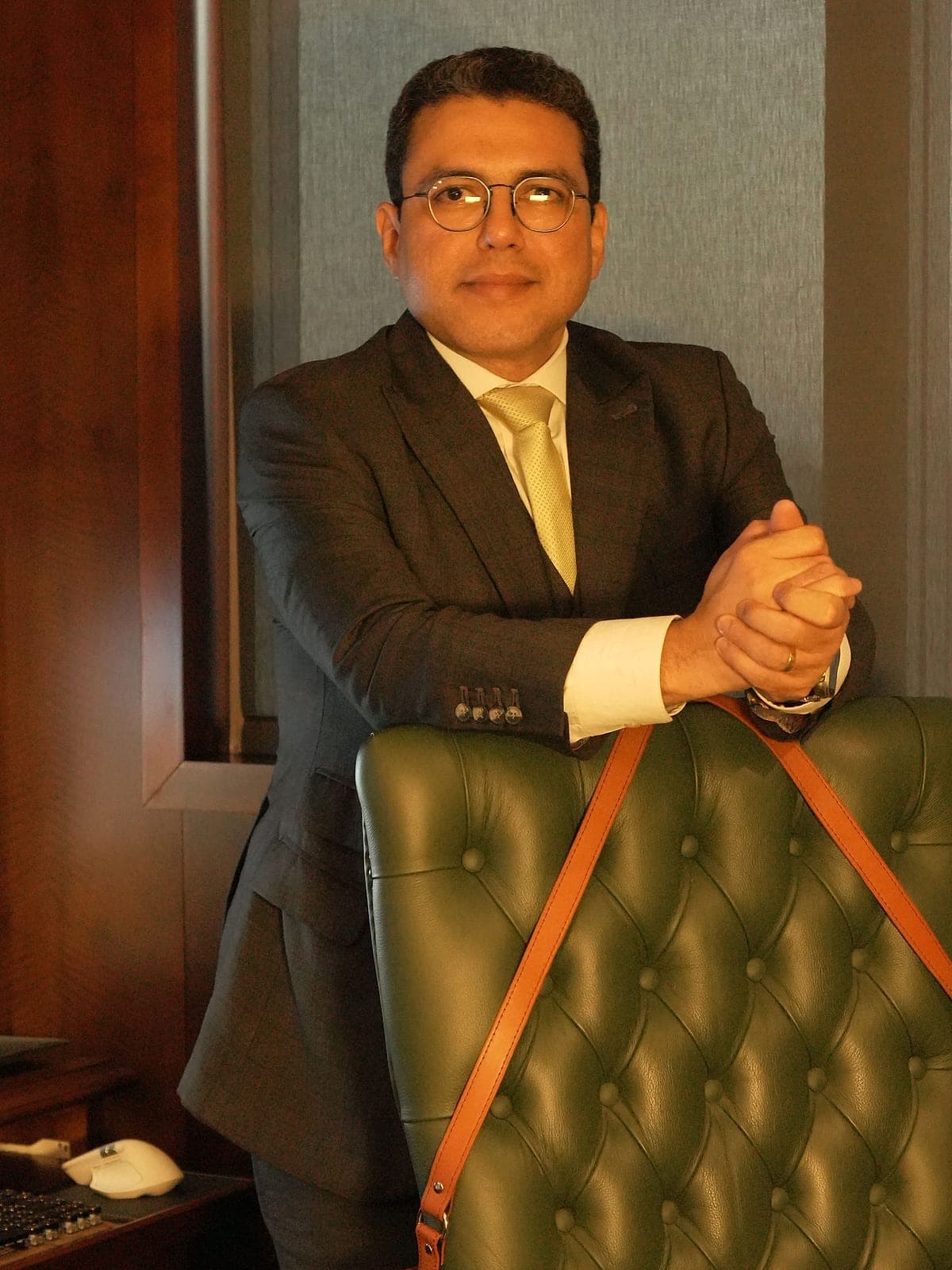 Dr. Helinelson Lombardo Santana de pé junto à mesa do gabinete