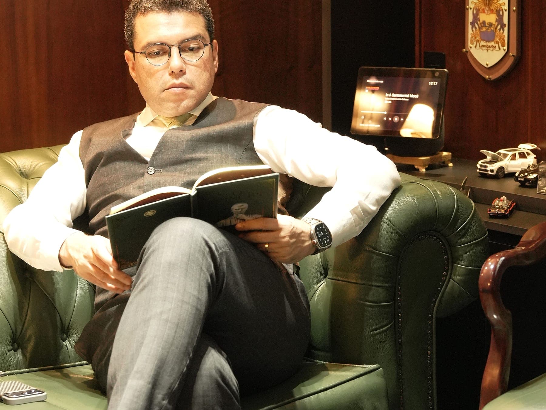 Dr. Helinelson Lombardo Santana lendo na poltrona da biblioteca do escritório